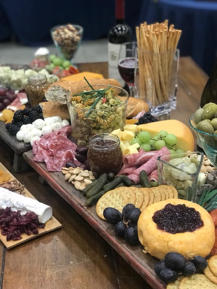 charcuterie board full of meat, crackers, cheese, fruit, nuts, and vegetables